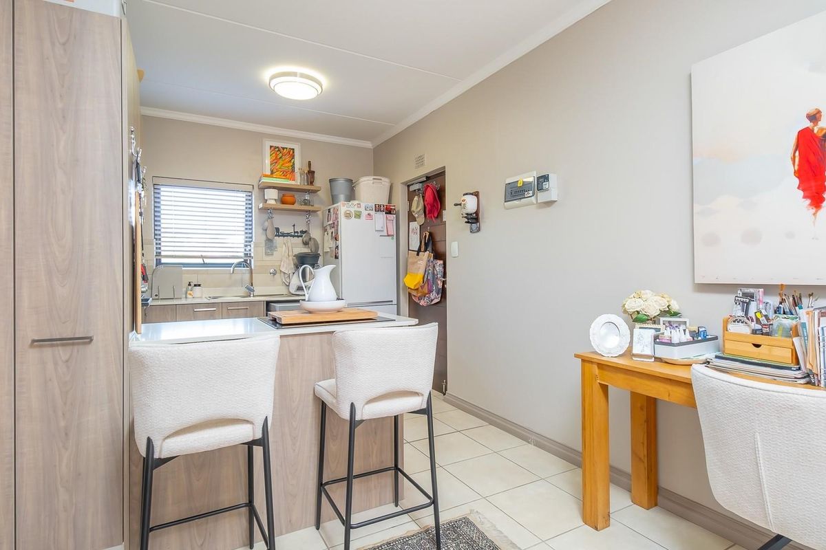 A functional kitchen featuring wood-look cabinetry, tiled flooring, and a breakfast bar area, providing a practical and well-maintained space for daily use.
