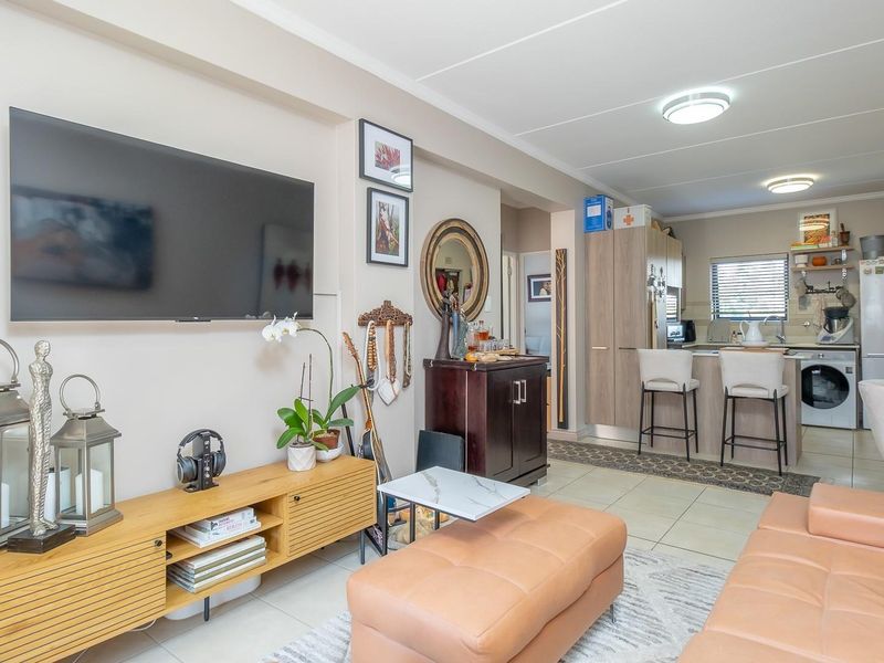 Open plan living area featuring a combined kitchen with island seating and tiled flooring, creating a functional and connected space for daily living.