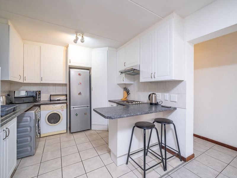 A functional kitchen featuring white cabinetry, dark laminate countertops, a breakfast bar, and tiled flooring, providing a practical layout for daily meal preparation.