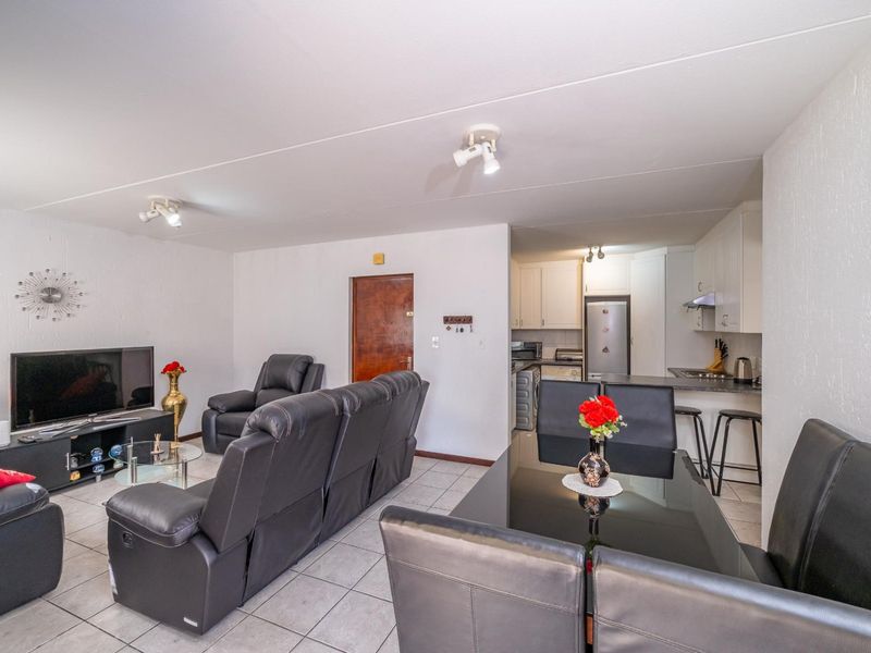 Open-plan living and dining area featuring tiled floors and a functional kitchen with built-in cabinetry and a breakfast bar.