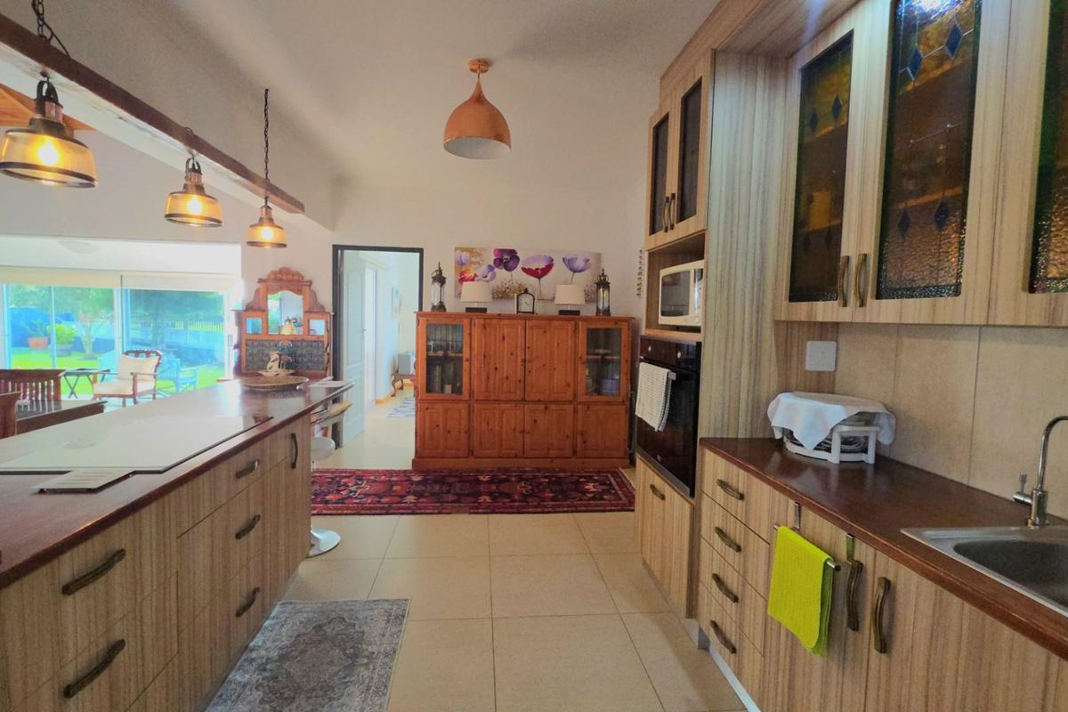 A functional kitchen featuring wood-look cabinetry, laminate countertops, built-in appliances, and pendant lighting, flowing into an adjacent living area.