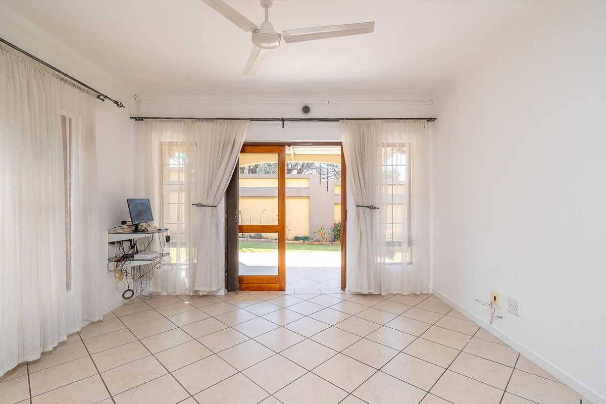 Bright and spacious living area featuring neutral tiled flooring, a ceiling fan, and direct access to the outdoor patio through sliding glass doors.