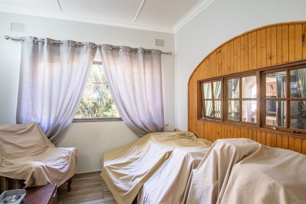 A bedroom featuring timber wall paneling, an internal window looking into an adjacent space, and tiled flooring.