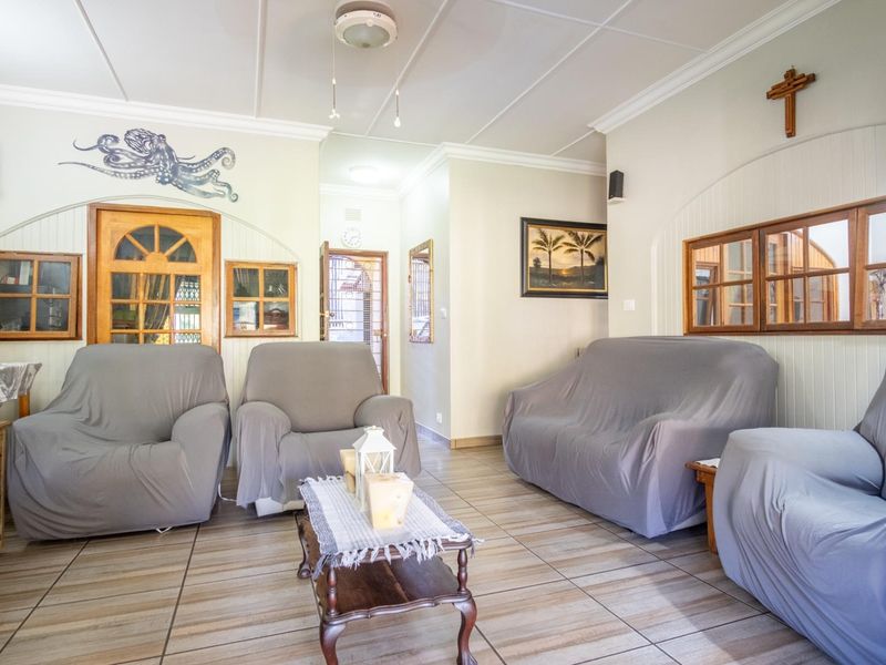 A living room featuring tiled flooring, timber-framed interior windows, and classic ceiling molding, offering a functional and well-maintained space.