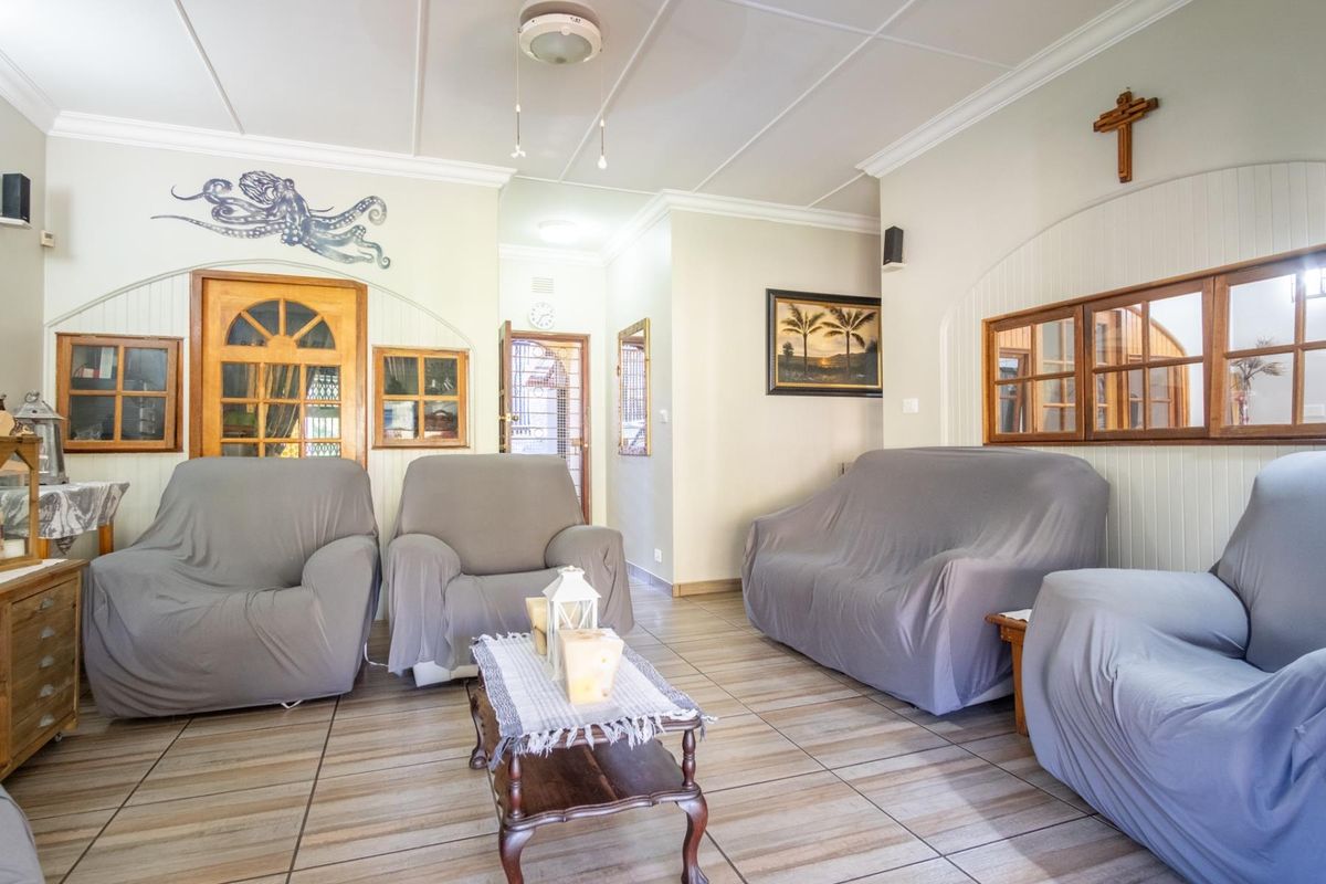 A living room featuring tiled flooring, timber-framed interior windows, and classic ceiling molding, offering a functional and well-maintained space.