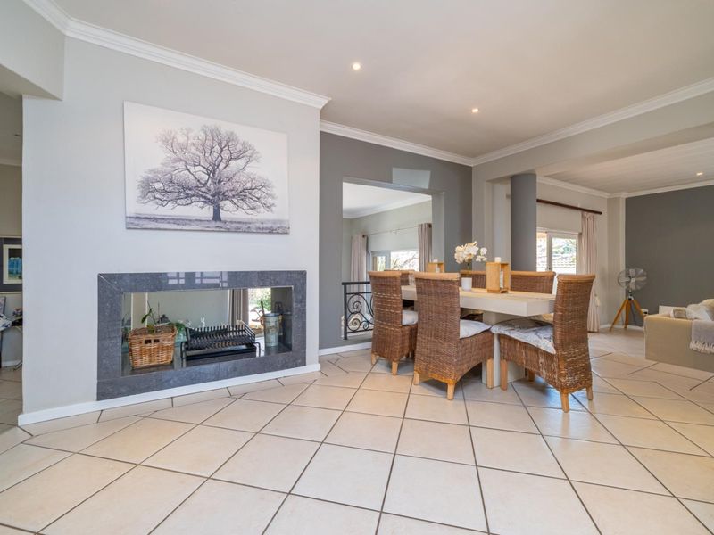 Spacious open-plan living and dining area featuring tiled flooring, recessed lighting, and a modern fireplace with a dark stone surround.