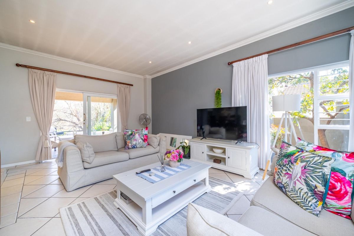 A bright and airy living room featuring tiled flooring, recessed downlighting, crown molding, and large sliding glass doors providing access to the outdoor area.