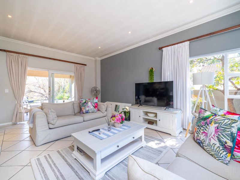 A bright and airy living room featuring tiled flooring, recessed downlighting, crown molding, and large sliding glass doors providing access to the outdoor area.