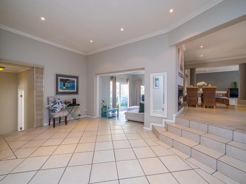 Spacious open-plan living area featuring tiled flooring, recessed lighting, and a built-in fireplace, with seamless flow between the entrance and dining space.