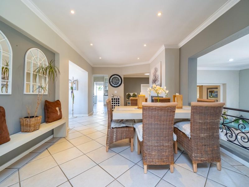 A bright dining area featuring ceramic floor tiles, recessed downlighting, and a built-in bench, with an open-plan layout leading to adjacent living spaces.
