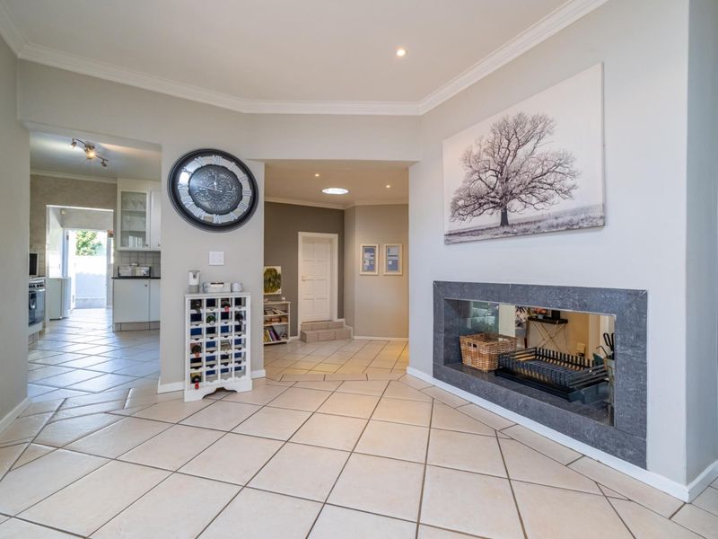 Spacious living area featuring a modern built-in fireplace with stone surround, tiled flooring, and a skylight, providing a bright and open atmosphere.