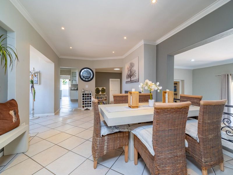 An open-plan dining area featuring ceramic floor tiles, recessed downlighting, and elegant crown molding, creating a bright and connected living space.