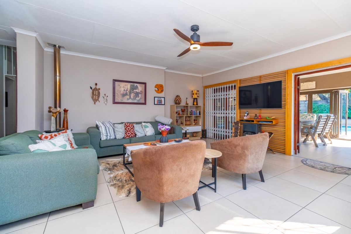 A comfortable living room featuring tiled flooring, a wood-burning fireplace, and a ceiling fan, with direct access to an outdoor patio area.