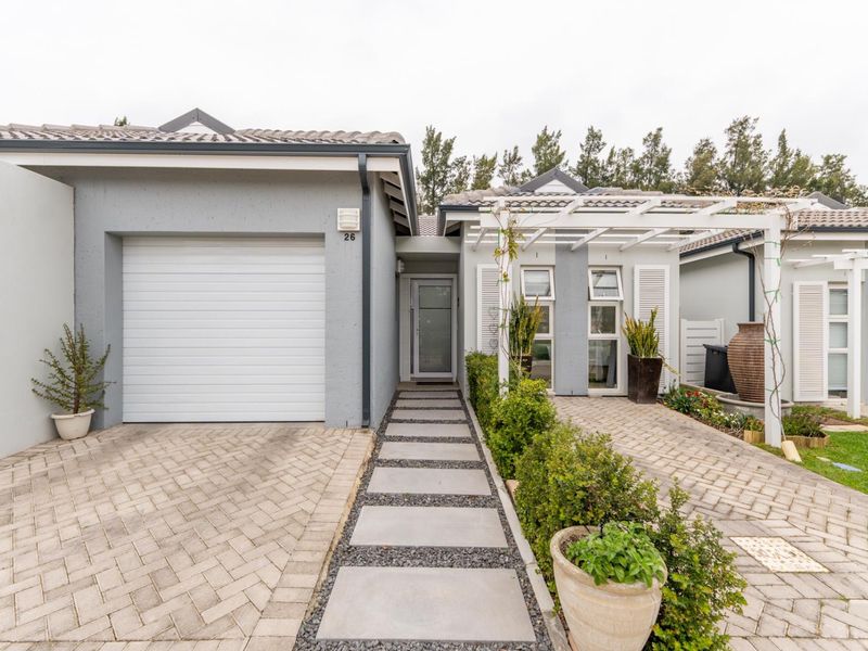 Front elevation of a modern home featuring a single garage, paved driveway, concrete walkway, and a decorative pergola over the entrance area.