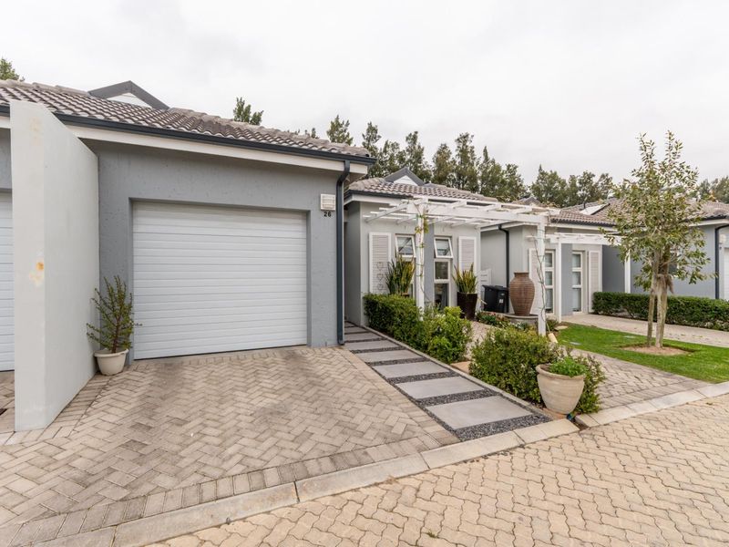 Front elevation of a modern residential property featuring a single garage, paved driveway, and a decorative pergola over the entrance walkway.