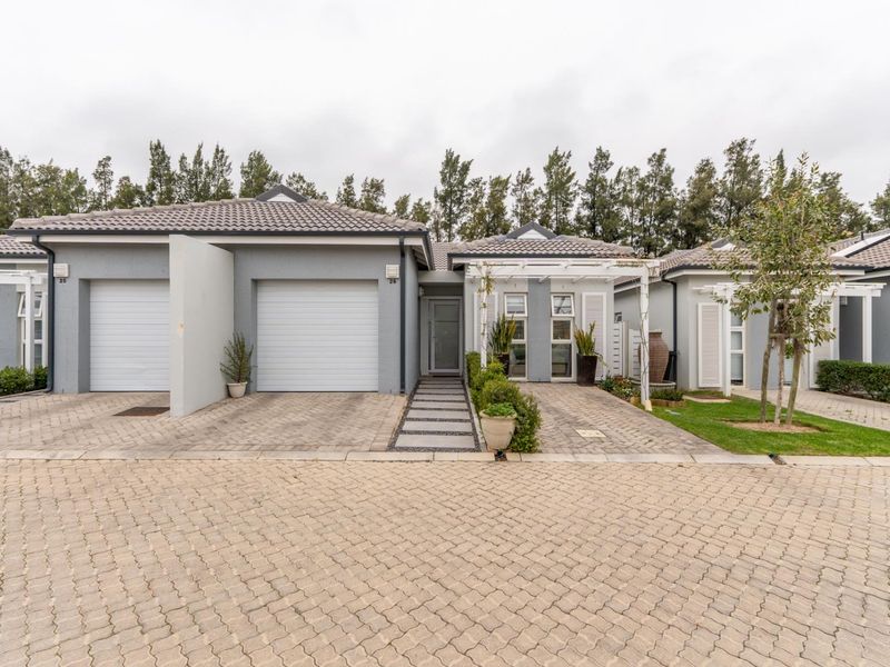 Front elevation of a modern residential property featuring a double garage, paved driveway, and a welcoming pergola-covered entrance walkway.