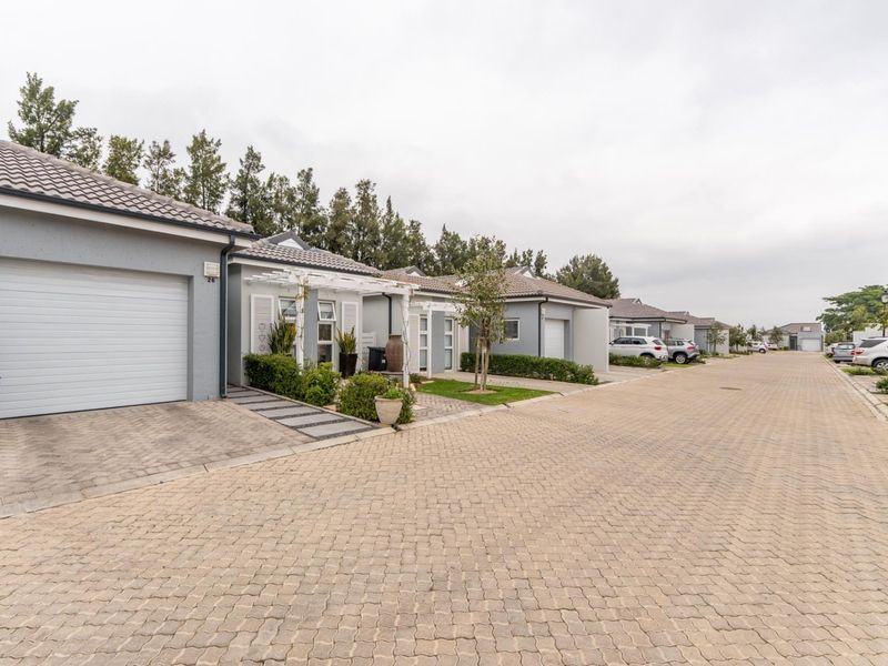 A view of a residential street featuring a row of modern single-story homes with paved driveways, tiled roofs, and integrated garages.