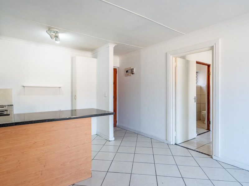 Open plan kitchen area featuring granite countertops, built-in hob, and tiled flooring, with direct access to adjacent rooms.