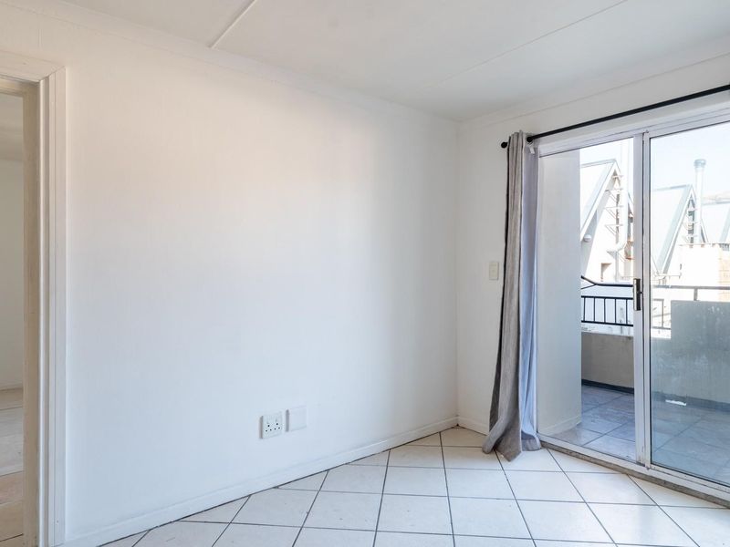 An empty living room featuring tiled flooring and a sliding glass door that provides access to an outdoor balcony area.