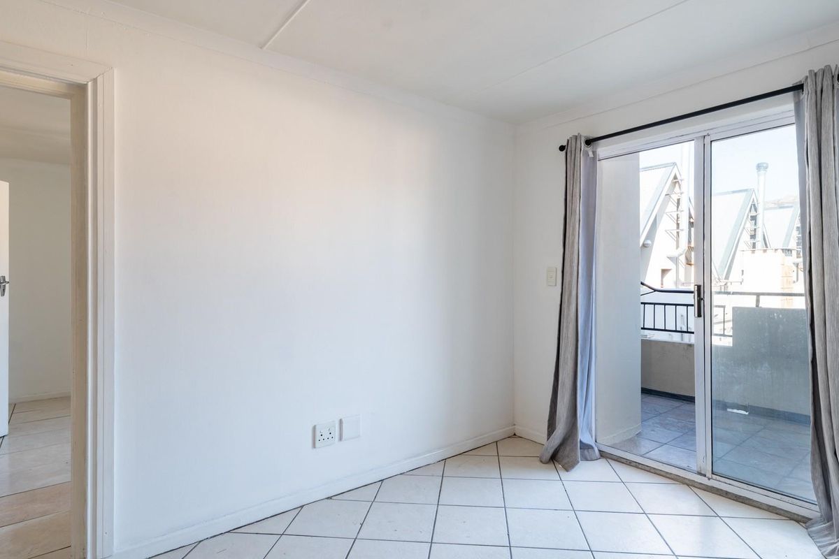 An empty living room featuring tiled flooring and a sliding glass door that provides access to an outdoor balcony area.
