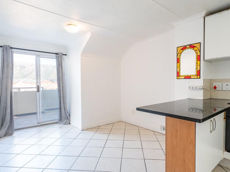 Open-plan kitchen and living area featuring tiled floors, built-in cabinetry, and a sliding door leading to a balcony.