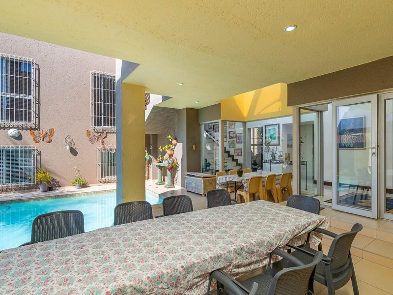 Covered outdoor patio area featuring tiled flooring, recessed lighting, and direct access to the swimming pool through sliding glass doors.