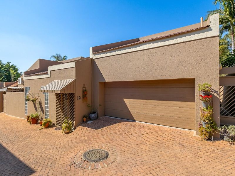 Front exterior view of the property featuring a paved driveway, integrated garage, and secure entrance with an awning.