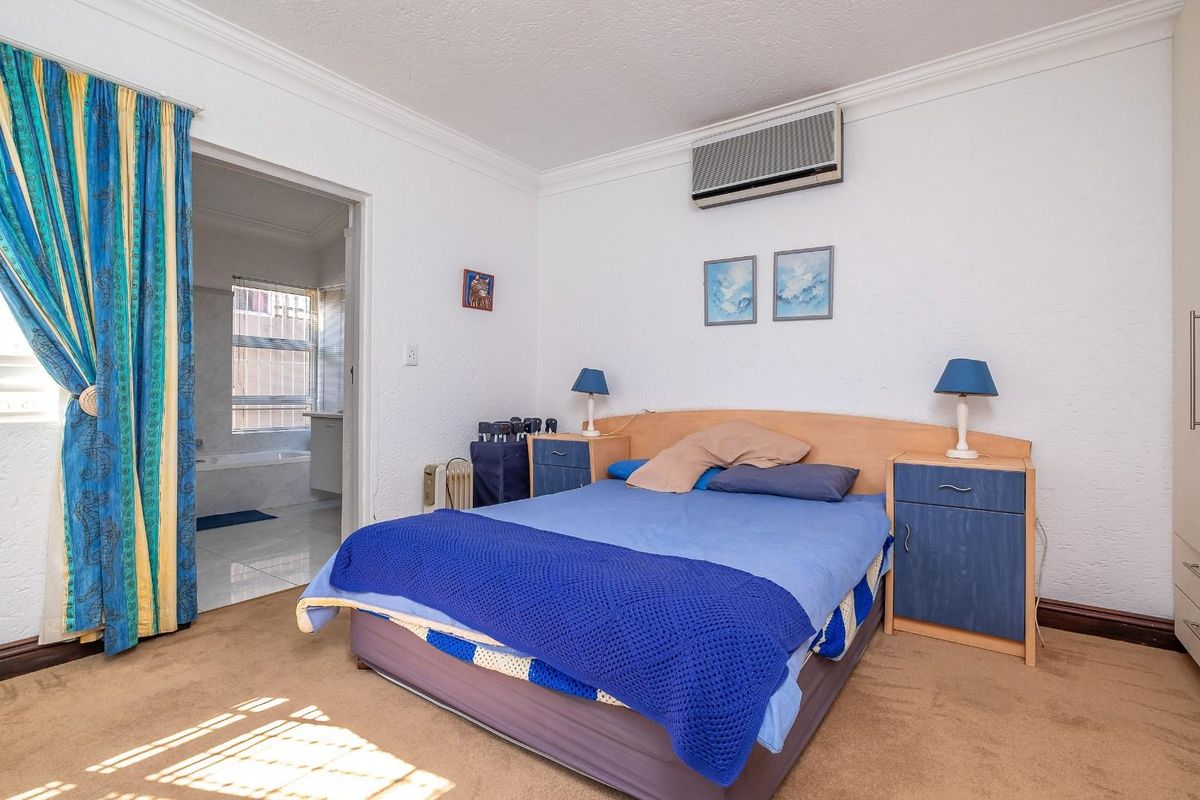 A bedroom featuring built-in wardrobes, wall-mounted air conditioning, and an en-suite bathroom access.