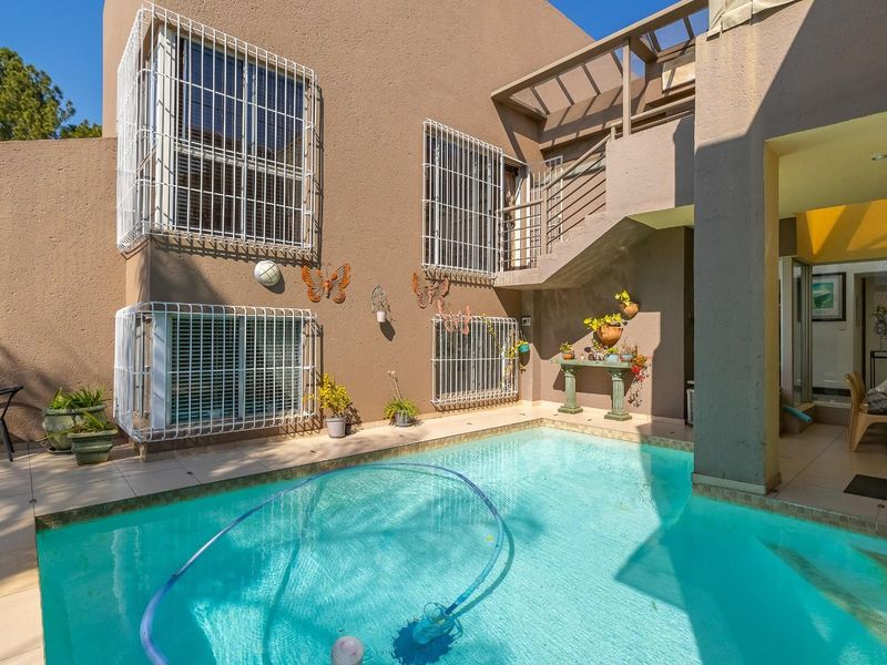A private outdoor pool area featuring a tiled patio, covered terrace space, and an external staircase leading to the upper level.