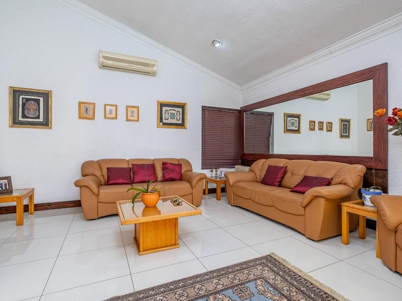 Spacious living room featuring polished tiled flooring, coved cornicing, a large wall-mounted mirror, and a split-system air conditioning unit.