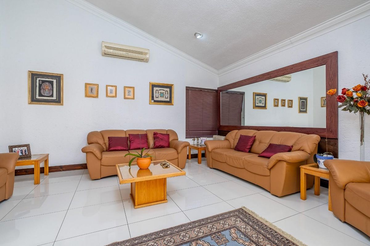 Spacious living room featuring polished tiled flooring, coved cornicing, a large wall-mounted mirror, and a split-system air conditioning unit.
