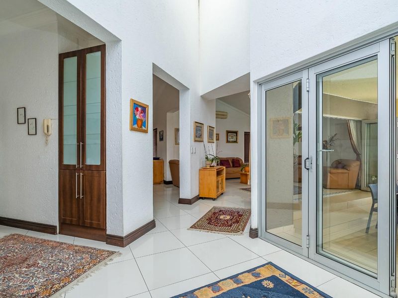 Spacious entrance hall featuring high ceilings, tiled flooring, and built-in cabinetry, providing seamless access to the living areas and outdoor patio.