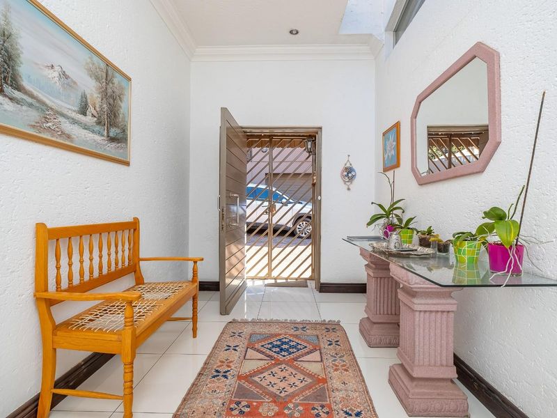Bright entrance hall featuring tiled flooring, a skylight for natural illumination, and a secure metal gate leading to the exterior.