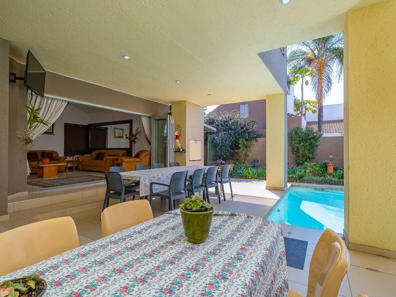 Spacious covered patio area featuring tiled flooring and recessed lighting, seamlessly connecting to the swimming pool and indoor living space.