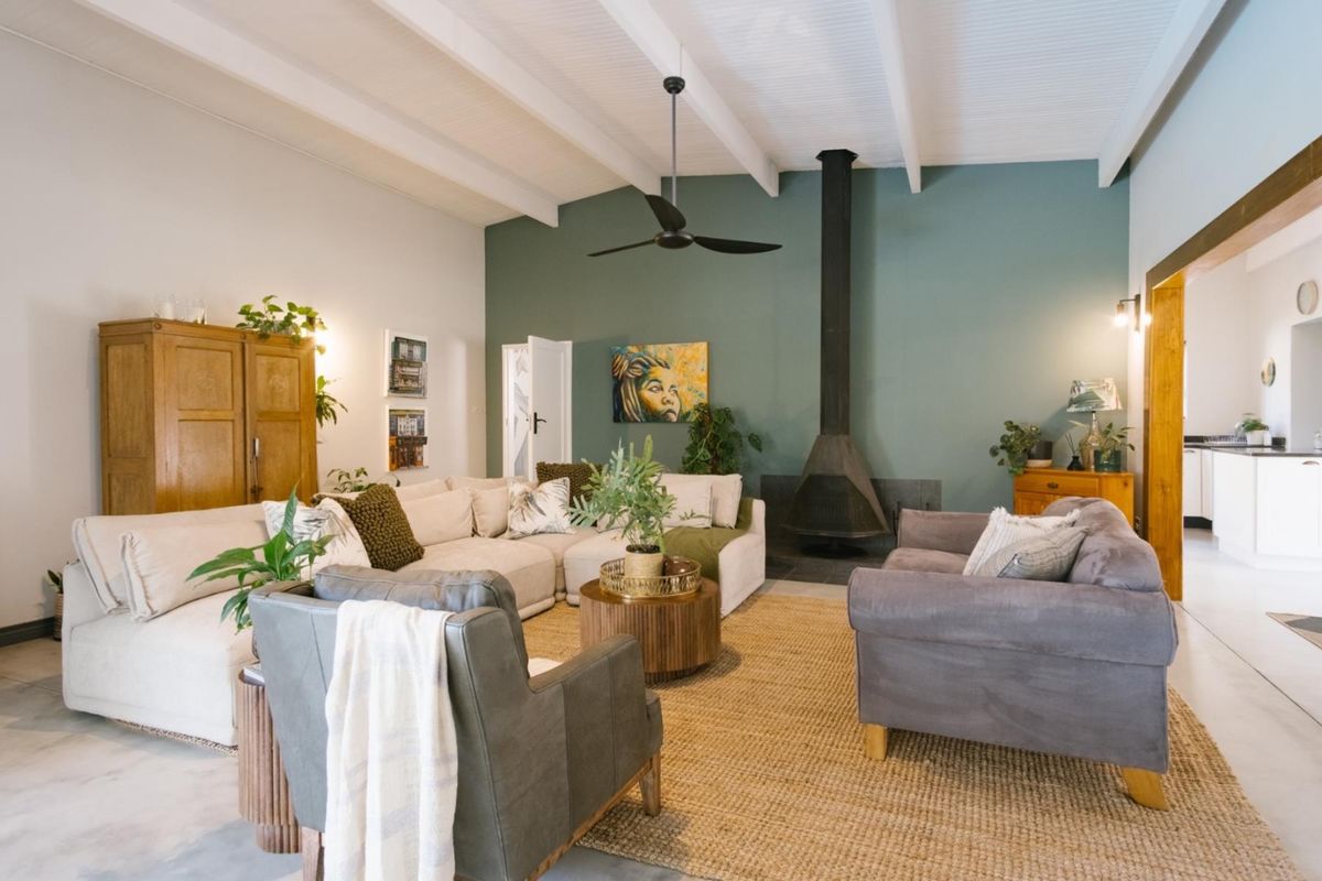 Spacious living room featuring a vaulted ceiling with exposed beams, a modern freestanding fireplace, and neutral tiled flooring.