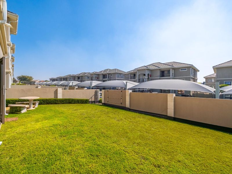 A private rear garden area featuring a well-maintained lawn and boundary wall, accessible via a sliding door from the apartment.