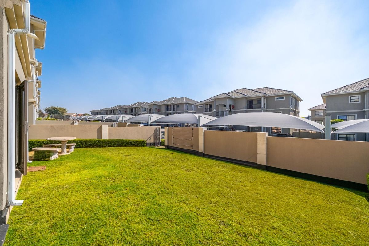 A private rear garden area featuring a well-maintained lawn and boundary wall, accessible via a sliding door from the apartment.