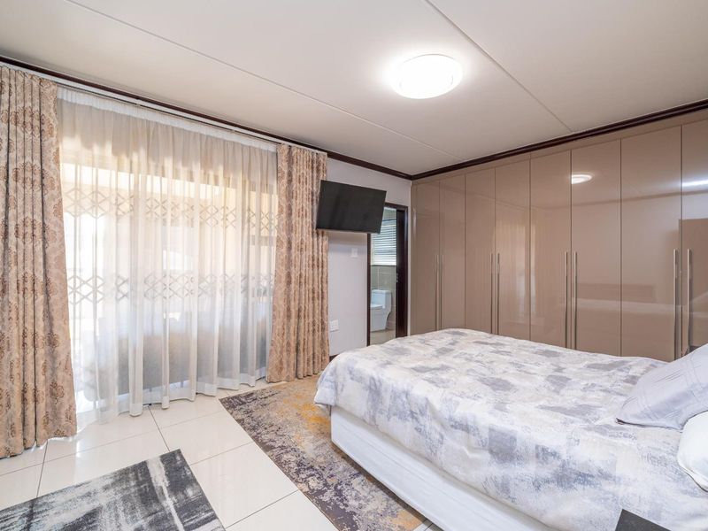 A well-maintained bedroom featuring glossy built-in cupboards, tiled flooring, and a sliding door providing access to an outdoor area.