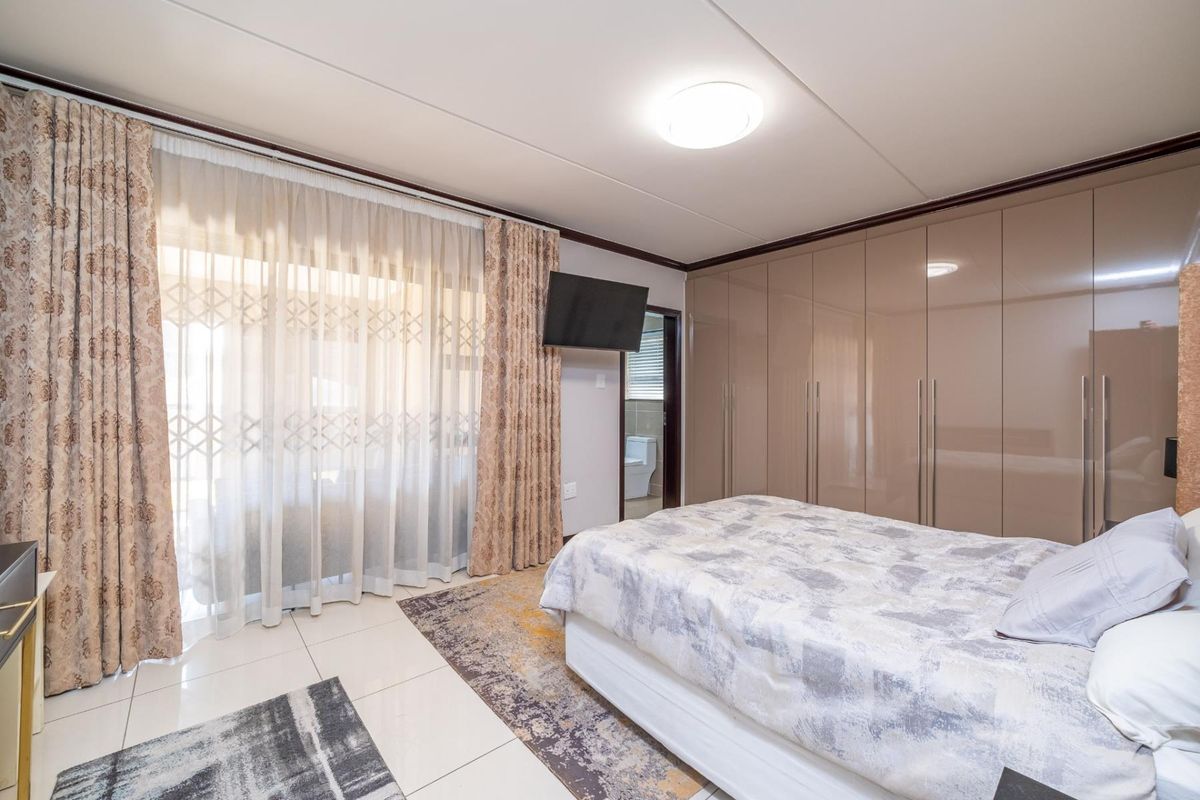 A well-maintained bedroom featuring glossy built-in cupboards, tiled flooring, and a sliding door providing access to an outdoor area.