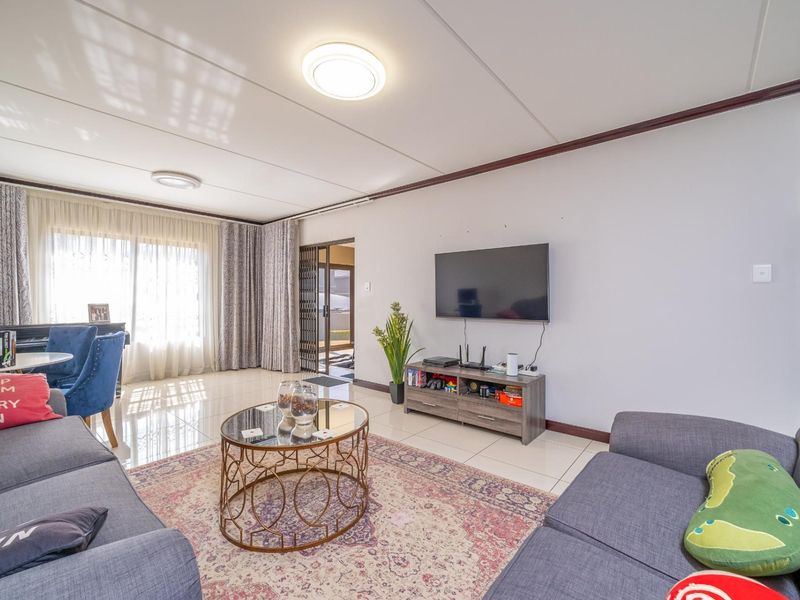 A bright and spacious living room featuring polished tiled flooring, neutral walls, and direct access to an outdoor area through a sliding door.