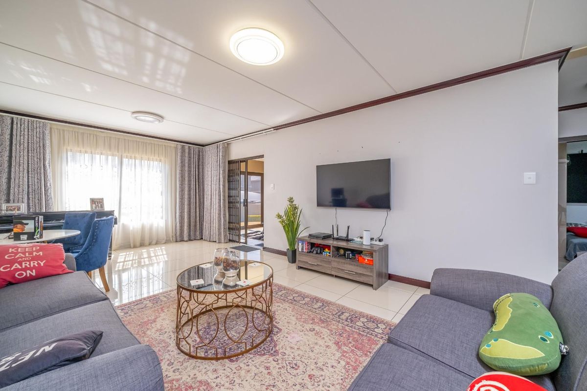 A bright and spacious living room featuring polished tiled flooring, neutral walls, and direct access to an outdoor area through a sliding door.