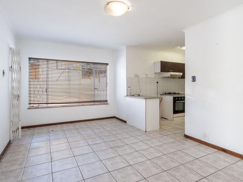 Open-plan living and kitchen area featuring tiled flooring, built-in kitchen cabinetry, and a gas hob, offering a blank canvas for renovation.