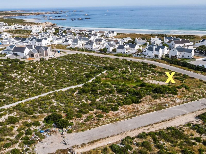 Aerial view of a vacant residential plot situated in a coastal estate, offering proximity to the beach and established neighborhood infrastructure.