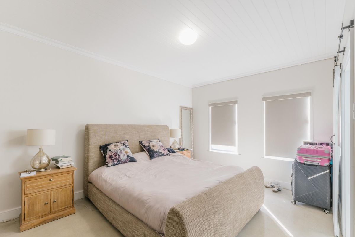 A bright and well-maintained bedroom featuring a tongue and groove ceiling, roller blinds, and a sliding barn door.