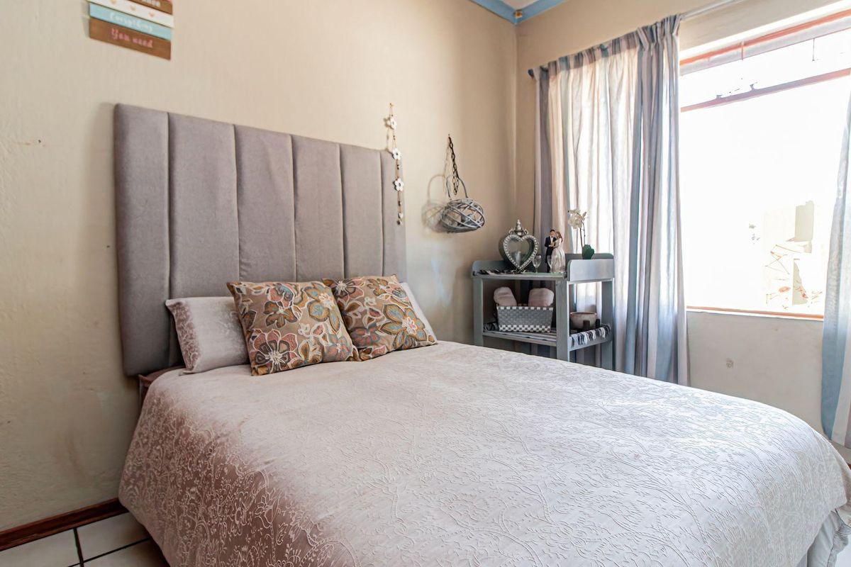 A bedroom featuring tiled flooring and a window with curtains, providing a functional space with neutral wall finishes.