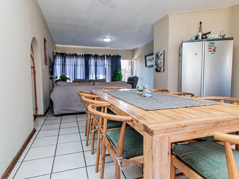 Open-plan living and dining area featuring tiled flooring, an arched entryway, and coved ceilings, providing a functional and connected living space.