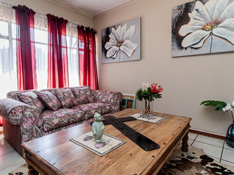 A comfortable living room featuring tiled flooring and a large window that allows for ample natural light.