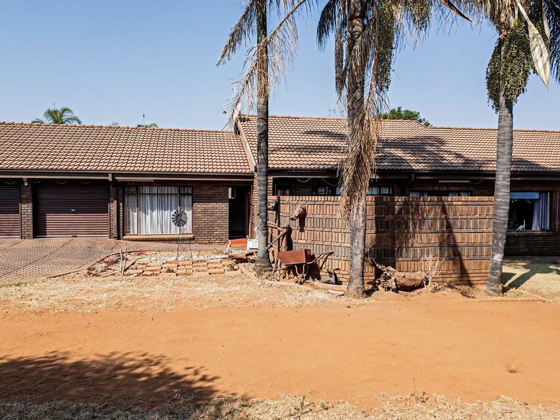 Front elevation of a single-story brick house featuring a double garage, tiled roof, and a paved driveway.