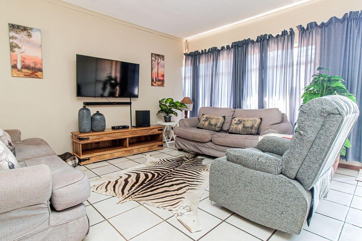 A comfortable living room featuring tiled flooring and a large window, providing a bright and functional space for relaxation.