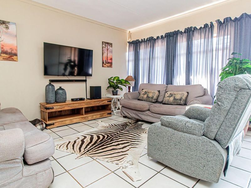 A comfortable living room featuring tiled flooring and a large window, providing a bright and functional space for relaxation.